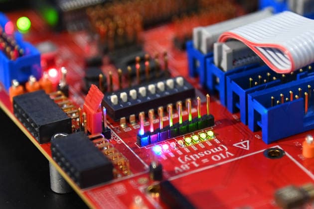 Nahaufnahme einer roten Elektronikplatine mit Steckverbindern, DIP-Schalter, Stiftleisten und Flachbandkabel. 5.Bayerischer Halbleiter-Kongress am 06.07.2026 in Muenchen. *** Close-up of a red circuit board with connectors, DIP switches, pin headers, and ribbon cables 5th Bavarian Semiconductor Congress on July 6, 2026, in Munich