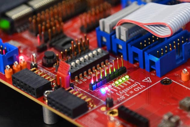 Nahaufnahme einer roten Elektronikplatine mit Steckverbindern, DIP-Schalter, Stiftleisten und Flachbandkabel. 5.Bayerischer Halbleiter-Kongress am 06.07.2026 in Muenchen. *** Close-up of a red circuit board with connectors, DIP switches, pin headers, and ribbon cables 5th Bavarian Semiconductor Congress on July 6, 2026, in Munich