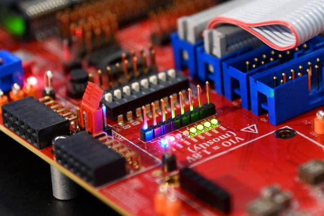 Nahaufnahme einer roten Elektronikplatine mit Steckverbindern, DIP-Schalter, Stiftleisten und Flachbandkabel. 5.Bayerischer Halbleiter-Kongress am 06.07.2026 in Muenchen. *** Close-up of a red circuit board with connectors, DIP switches, pin headers, and ribbon cables 5th Bavarian Semiconductor Congress on July 6, 2026, in Munich