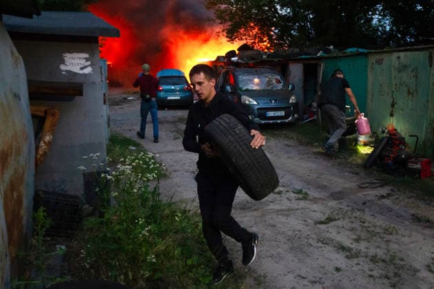 RECORD DATE NOT STATED A man carries a car tire as garages burn following a massive combined Russian attack on Kyiv, Ukraine, on July 6, 2026. Russian forces launched a large-scale attack on the capital using ballistic and cruise missiles as well as attack drones, causing destruction to residential buildings and civilian infrastructure in several districts of the city. The Podilskyi district was hit hardest. At least 11 people were killed and 46 others were injured (Photo by Kyrylo Chubotin Ukrinform) Russia launches another massive strike on Kyiv  Copyright: xKyryloxChubotinx