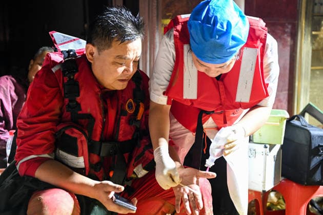 (260707) -- HENGZHOU, July 7, 2026 -- A medical personnel disinfects a cut in the hand of a rescuer in Hengzhou of Nanning City, south China s Guangxi Zhuang Autonomous Region, July 7, 2026. Record-breaking rainfall and the ensuing floods in parts of Nanning, capital city of south China s Guangxi Zhuang Autonomous Region, have left four people dead and eight others missing as of 10 a.m. Tuesday, according to a press conference on flood prevention and disaster relief held in Nanning. Hengzhou City and Binyang County, both currently under the jurisdiction of Nanning, recently experienced rainfall that broke local 24-hour meteorological records. The reported casualties were all in Hengzhou. ) CHINA-GUANGXI-NANNING-FLOOD-RESCUE (CN) CaoxYim 