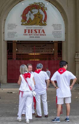 Revelers outside the bullring in Pamplona, northern Spain on July 8, 2026 shows several fighting bulls, or toros bravos , from the ranch of Cebada Gago as they stampede near the bullring, at the end of the course through the Old City streets. Several runners touch the bull s side as they sprint into the bullring.  PAM2026070801 JimxHollander