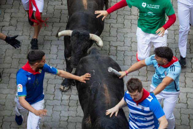 The second running-of-the-bulls in Pamplona, northern Spain on Wednesday morning, July 8, 2026 shows several fighting bulls, or toros bravos , from the ranch of Cebada Gago as they stampede near the bullring at the end of the course through the Old City street. Several runners touch the bull s side as they sprint into the bullring.  PAM2026070803 JimxHollander