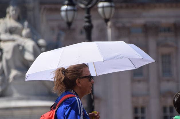 July 8, 2026, London, United Kingdom: A woman carries an umbrella to shield herself from heat as she walks outside Buckingham Palace. London United Kingdom  - ZUMAs197 20260708_aab_s197_005 Copyright: xVukxValcicx