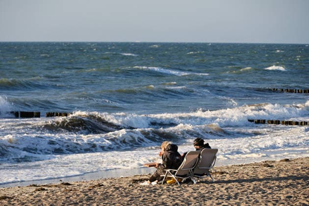 20260708 Strandidylle an der Ostsee bei Börgerenede-Rethwisch, einer Gemeinde im Landkreis Rostock in Mecklenburg-Vorpommern. Touristen und Urlauber flannieren am Strand, sitzen in Campingstühlen, bauen Sandburgen und suchen Bernstein. Sogar Kitesurfer gehen bei dem Wellengang auf dem Wasser ihrem Sport nach. Hier genießen zwei Gäste am Strand eine mitgebrachte Pizza. Börgerende-Rethwisch Mecklenburg-Vorpommern Deutschland *** 20260708 A picturesque beach scene on the Baltic Sea near Börgerende Rethwisch, a municipality in the Rostock district of Mecklenburg-Western Pomerania. Tourists and vacationers stroll along the beach, sitting in camping chairs, building sandcastles, and searching for amber. Even kitesurfers are enjoying their