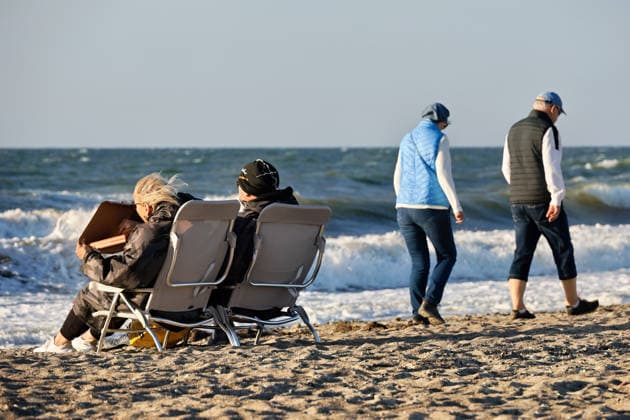 20260708 Strandidylle an der Ostsee bei Börgerenede-Rethwisch, einer Gemeinde im Landkreis Rostock in Mecklenburg-Vorpommern. Touristen und Urlauber flannieren am Strand, sitzen in Campingstühlen, bauen Sandburgen und suchen Bernstein. Sogar Kitesurfer gehen bei dem Wellengang auf dem Wasser ihrem Sport nach. Hier genießen zwei Gäste am Strand eine mitgebrachte Pizza. Börgerende-Rethwisch Mecklenburg-Vorpommern Deutschland *** 20260708 A picturesque beach scene on the Baltic Sea near Börgerende Rethwisch, a municipality in the Rostock district of Mecklenburg-Western Pomerania. Tourists and vacationers stroll along the beach, sitting in camping chairs, building sandcastles, and searching for amber. Even kitesurfers are enjoying their