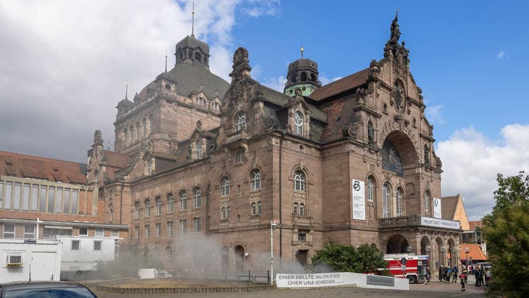 Feuerwehr-Großeinsatz am Nürnberger Opernhaus nach Brand in Tiefgarage, Nürnberg, 09.07.2026 Starke Rauchentwicklung aus den Lüftungsschächten vor dem Staatstheater Nürnberg nach einem Tiefgaragenbrand. Ein brennendes Auto löste das Feuer aus, das auf weitere Fahrzeuge übergriff. Die Feuerwehr hat den Brand weitgehend unter Kontrolle; das Staatstheater wurde wegen des Qualms evakuiert. Nürnberg Bayern Deutschland *** Major Fire Department Operation at the Nuremberg Opera House Following a Fire in the Underground Parking Garage, Nuremberg, July 9, 2026 Heavy smoke billowing from the ventilation shafts in front of the Nuremberg State Theater following a fire in the underground parking garage. A burning car sparked the fire, which sp 20260709-286A1354-M4000