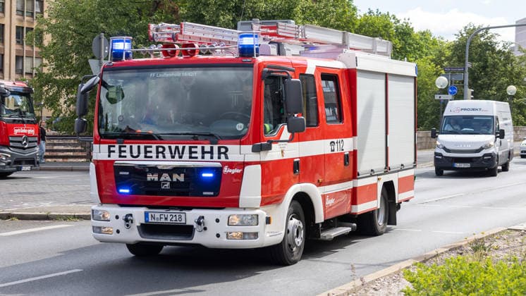 Feuerwehr-Großeinsatz am Nürnberger Opernhaus nach Brand in Tiefgarage, Nürnberg, 09.07.2026 Löschgruppenfahrzeug der Freiwilligen Feuerwehr Laufamholz (MAN Ziegler, Kennzeichen N-FW 218) mit Blaulicht auf der Anfahrt zum Einsatz. In einer Tiefgarage nahe dem Staatstheater Nürnberg war ein Auto in Brand geraten, das Feuer griff auf weitere Fahrzeuge über. Starke Rauchentwicklung aus Lüftungsschächten erschwerte den Einsatz. Nürnberg Bayern Deutschland *** Major Fire Department Operation at the Nuremberg State Theater Following a Fire in an Underground Parking Garage, Nuremberg, July 9, 2026. A fire engine from the Laufamholz Volunteer Fire Department (MAN Ziegler), license plate N FW 218 with its blue lights flashing on the way to 20260709-286A1363-M4000