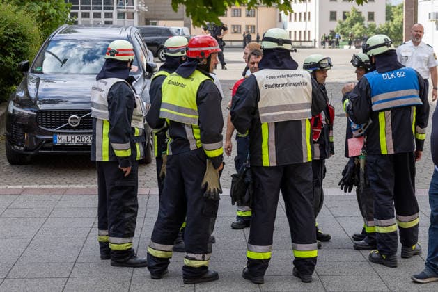Feuerwehr-Großeinsatz am Nürnberger Opernhaus nach Brand in Tiefgarage, Nürnberg, 09.07.2026 Einsatzkräfte der Feuerwehr Nürnberg, darunter der Stadtbrandinspektor, besprechen die Lage nach einem Tiefgaragenbrand. Ein brennendes Auto hatte das Feuer ausgelöst, das auf weitere Fahrzeuge übergriff. Starke Rauchentwicklung aus Lüftungsschächten erschwerte den Einsatz; das angrenzende Staatstheater Nürnberg wurde evakuiert. Nürnberg Bayern Deutschland *** Major Fire Department Operation at the Nuremberg Opera House Following a Fire in an Underground Parking Garage, Nuremberg, July 9, 2026 Emergency responders from the Nuremberg Fire Department, including the city fire inspector, discuss the situation following a fire in an undergrou 20260709-286A1408-M4000