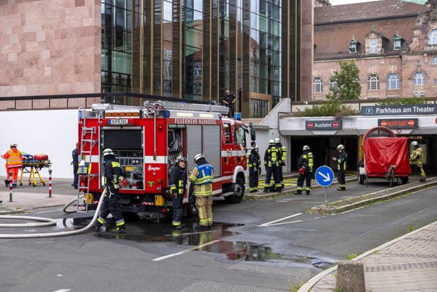 Feuerwehr-Großeinsatz am Nürnberger Opernhaus nach Brand in Tiefgarage, Nürnberg, 09.07.2026 Einsatzkräfte der Feuerwehr Nürnberg vor der Ausfahrt des Parkhauses am Theater. Ein brennendes Auto in der Tiefgarage hatte das Feuer ausgelöst, das auf weitere Fahrzeuge übergriff. Das angrenzende Staatstheater Nürnberg wurde wegen starker Rauchentwicklung evakuiert; Statiker überprüfen die Stabilität der Tiefgarage. Nürnberg Bayern Deutschland *** Major Fire Department Operation at the Nuremberg Opera House Following a Fire in the Underground Parking Garage, Nuremberg, July 9, 2026 Nuremberg Fire Department personnel in front of the parking garage exit at the theater A burning car in the underground parking garage had sparked the fir 20260709-286A1440-M4000