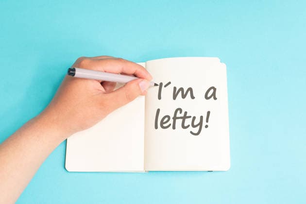 Ich bin Linkshänder, stehe auf einem Notizblock, schreibe mit der linken Hand, mit einem Stift auf dem Tisch, nach dem Linkshänder-Prinzip, und schreibe eine Nachricht von Hand I am a lefty standing on notebook, writing with left hand, pen and table, left handed concept, handwriting a message (License=RF) Copyright: xZoonar.com BeritxKesslerx 25227103