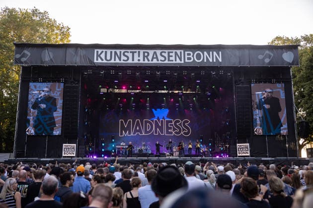 Madness auf dem Kunst!Rasen Bonn Die britische Ska-Pop-Band Madness mit Sänger Graham Suggs McPHERSON beim Live-Auftritt beim Open-Air-Konzert auf dem Kunst!Rasen Bonn-Gronau. Die sommerliche Konzertreihe Kunst!Rasen findet am Rande der Rheinaue am Bonner Rheinufer statt. Bonn Nordrhein-Westfalen Deutschland *** Madness at the Kunst Rasen in Bonn: The British ska-pop band Madness, featuring singer Graham Suggs McPHERSON, performs live at an open-air concert at the Kunst Rasen in Bonn-Gronau. The summer concert series Kunst Rasen takes place on the edge of the Rheinaue on the banks of the Rhine in Bonn, North Rhine-Westphalia, Germany. Copyright: xMarcxJohnx