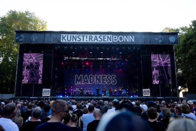 Madness auf dem Kunst!Rasen Bonn Die britische Ska-Pop-Band Madness mit Sänger Graham Suggs McPHERSON beim Live-Auftritt beim Open-Air-Konzert auf dem Kunst!Rasen Bonn-Gronau. Die sommerliche Konzertreihe Kunst!Rasen findet am Rande der Rheinaue am Bonner Rheinufer statt. Bonn Nordrhein-Westfalen Deutschland *** Madness at the Kunst Rasen in Bonn: The British ska-pop band Madness, featuring singer Graham Suggs McPHERSON, performs live at an open-air concert at the Kunst Rasen in Bonn-Gronau. The summer concert series Kunst Rasen takes place on the edge of the Rheinaue on the banks of the Rhine in Bonn, North Rhine-Westphalia, Germany. Copyright: xMarcxJohnx