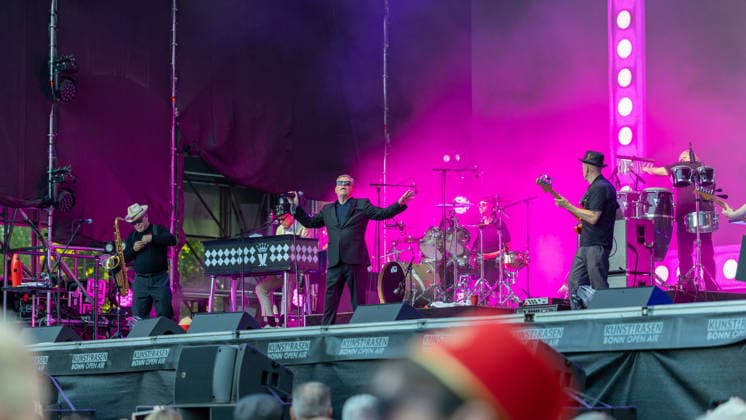 Madness auf dem Kunst!Rasen Bonn Die britische Ska-Pop-Band Madness mit Sänger Graham Suggs McPHERSON beim Live-Auftritt beim Open-Air-Konzert auf dem Kunst!Rasen Bonn-Gronau. Die sommerliche Konzertreihe Kunst!Rasen findet am Rande der Rheinaue am Bonner Rheinufer statt. Bonn Nordrhein-Westfalen Deutschland *** Madness at the Kunst Rasen in Bonn: The British ska-pop band Madness, featuring singer Graham Suggs McPHERSON, performs live at an open-air concert at the Kunst Rasen in Bonn-Gronau. The summer concert series Kunst Rasen takes place on the edge of the Rheinaue on the banks of the Rhine in Bonn, North Rhine-Westphalia, Germany. Copyright: xMarcxJohnx