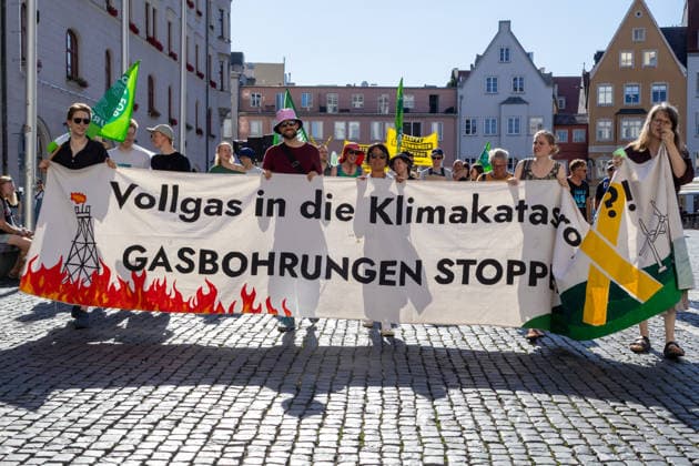 Augsburg, Bavaria, Germany - July 10, 2026: Demonstration by the climate justice movement Fridays for Future and GREENPEACE in Augsburg. Under the nationwide slogan: Protect the climate, fire the rich, the activists are protesting, among other things, against current gas infrastructure policy and planned gas drilling in Bavaria. Protesters holding a banner that reads: FULL THROTTLE TOWARD A CLIMATE CATASTROPHE? STOP GAS DRILLING! *** Demonstration der Klimaschutzbewegung Fridays for Future und GREENPEACE in Augsburg. Unter dem bundesweiten Motto: Klima schützen, Reiche entlassen, protestieren die Aktivisten unter anderem gegen die aktuelle Gas-Infrastrukturpolitik und geplante Gasbohrungen in Bayern. Demonstranten mit Banner: