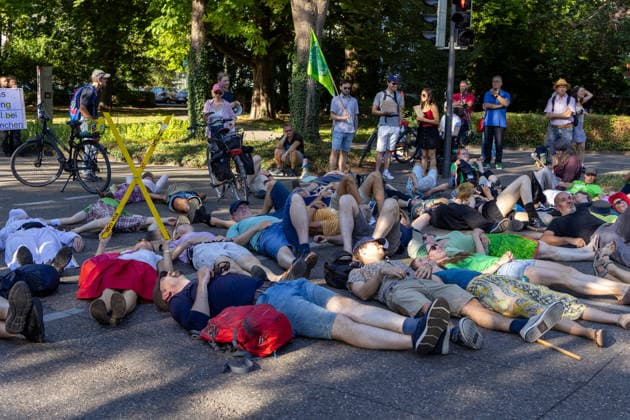 Augsburg, Bavaria, Germany July 10, 2026: Demonstration by the climate justice movement Fridays for Future and Greenpeace in Augsburg. Under the nationwide slogan Protect the climate, fire the rich, activists are protesting, among other things, against current gas infrastructure policies and planned gas drilling in Bavaria. Activists have lain down in the street to symbolize climate-related deaths caused by heat *** Demonstration der Klimaschutzbewegung Fridays for Future und GREENPEACE in Augsburg. Unter dem bundesweiten Motto: Klima schützen, Reiche entlassen, protestieren die Aktivisten unter anderem gegen die aktuelle Gas-Infrastrukturpolitik und geplante Gasbohrungen in Bayern. Aktivisten haben sich auf die Straße gelegt um