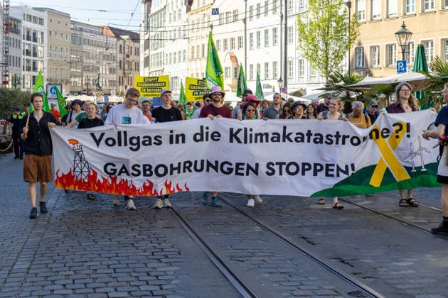 Augsburg, Bavaria, Germany - July 10, 2026: Demonstration by the climate justice movement Fridays for Future and GREENPEACE in Augsburg. Under the nationwide slogan: Protect the climate, fire the rich, the activists are protesting, among other things, against current gas infrastructure policy and planned gas drilling in Bavaria. Protesters holding a banner that reads: FULL THROTTLE TOWARD A CLIMATE CATASTROPHE? STOP GAS DRILLING! *** Demonstration der Klimaschutzbewegung Fridays for Future und GREENPEACE in Augsburg. Unter dem bundesweiten Motto: Klima schützen, Reiche entlassen, protestieren die Aktivisten unter anderem gegen die aktuelle Gas-Infrastrukturpolitik und geplante Gasbohrungen in Bayern. Demonstranten mit Banner: