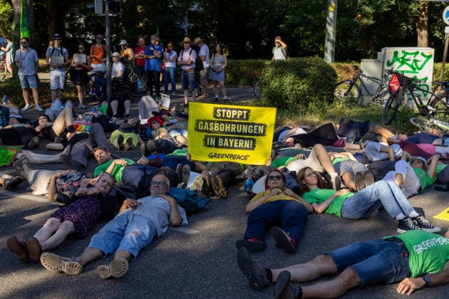 Augsburg, Bavaria, Germany July 10, 2026: Demonstration by the climate justice movement Fridays for Future and Greenpeace in Augsburg. Under the nationwide slogan Protect the climate, fire the rich, activists are protesting, among other things, against current gas infrastructure policies and planned gas drilling in Bavaria. Activists have lain down in the street to symbolize climate-related deaths caused by heat *** Demonstration der Klimaschutzbewegung Fridays for Future und GREENPEACE in Augsburg. Unter dem bundesweiten Motto: Klima schützen, Reiche entlassen, protestieren die Aktivisten unter anderem gegen die aktuelle Gas-Infrastrukturpolitik und geplante Gasbohrungen in Bayern. Aktivisten haben sich auf die Straße gelegt um