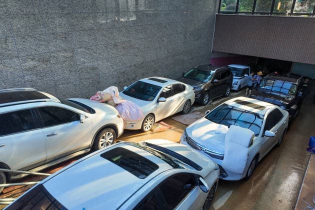 GUIGANG, CHINA - JULY 10: Vehicles pass through cushions made of quilts at the entrance of a garage protected by a makeshift waterproof wall built by residents on July 10, 2026 in Guigang, Guangxi Zhuang Autonomous Region of China. The local authorities beef up restoration efforts after torrential rains caused by Typhoon Maysak.  Copyright: xChinaxNewsxServicex 111653540918