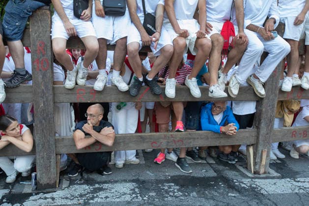 Spectators, many wearing the traditional white clothes in fiesta, sit on a barricade along the bull-running course as they wait to see the fights bulls from the ranch of JosÃ Escolar Gil stampede past in the fifth encierro , or running-of-the-bulls in the Fiesta de San Fermin and Feria del Toro in Pamplona, northern Spain, on Saturday July 11, 2026.  PAM20260711158 JimxHollander