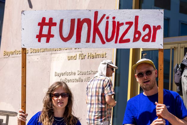Demonstration für Solidarität statt Sozialabbau, Nürnberg, 11.07.2026 Zwei Demonstranten halten ein Schild mit dem Hashtag UNKÜRZBAR vor dem Bayerischen Staatsministerium für Finanzen und Heimat. Das Bündnis UNKÜRZBAR Mittelfranken protestiert gegen das Reformpaket der Bundesregierung und fordert Solidarität statt Sozialabbau. Nürnberg Bayern Deutschland *** Demonstration for Solidarity Instead of Social Cuts, Nuremberg, July 11, 2026 Two demonstrators hold a sign with the hashtag UNKÜRZBAR in front of the Bavarian State Ministry of Finance and Home Affairs. The UNKÜRZBAR Middle Franconia coalition is protesting the federal government’s reform package and calling for solidarity instead of cuts to social services. Nuremberg, Bav 20260711-286A1926-M4000