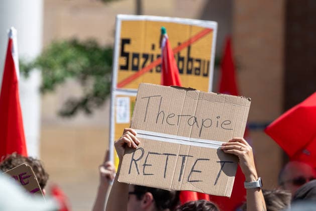Demonstration für Solidarität statt Sozialabbau, Nürnberg, 11.07.2026 Demonstrantin hält ein Pappschild mit der Aufschrift Therapie rettet in die Höhe. Im Hintergrund ein weiteres Schild mit dem durchgestrichenen Schriftzug Sozialabbau sowie rote Fahnen. Das Bündnis UNKÜRZBAR Mittelfranken protestiert gegen Kürzungen im Sozialbereich. Nürnberg Bayern Deutschland *** Demonstration for Solidarity Instead of Social Cuts, Nuremberg, July 11, 2026 A demonstrator holds aloft a cardboard sign reading Therapy Saves. In the background is another sign with the words Social Cuts crossed out, as well as red flags. The UNKÜRZBAR Middle Franconia Alliance is protesting against cuts to social services in Nuremberg Bavaria, Germany 20260711-1V9A5235-M4000