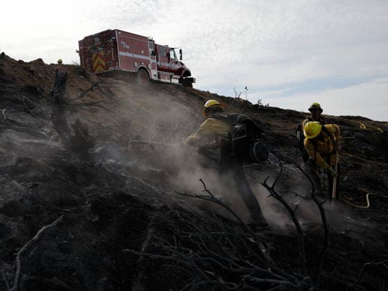 (260712) -- ANTELOPE VALLEY, July 12, 2026 -- Firefighters mop up debris after battling a brush fire in Antelope Valley, Los Angeles County, California, the United States, July 11, 2026. A wildfire burning in U.S. Southern California exploded to nearly 2,700 acres (about 10.9 square kilometers) Saturday, forcing evacuations amid dangerous heat wave. (Photo by Xinhua) U.S.-CALIFORNIA-LOS ANGELES COUNTY-WILDFIRE QiuxChen 