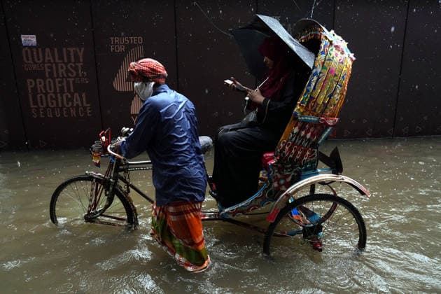 July 12, 2026, Dhaka, Dhaka, Bangladesh: A rickshaw puller pedals through a waterlogged street while carrying passengers during heavy monsoon rainfall in Dhaka, Bangladesh. Persistent downpours have inundated large parts of the capital, disrupting daily life and transportation, forcing residents to continue their routines despite widespread flooding. Dhaka Bangladesh  - ZUMAk174 20260712_zip_k174_001 Copyright: xSyedxMahabubulxKaderx