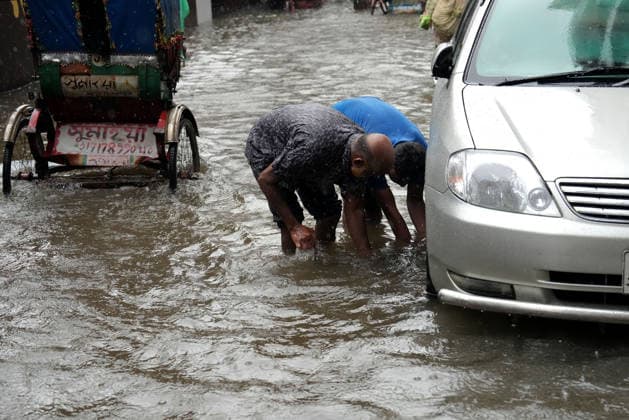 July 12, 2026, Dhaka, Dhaka, Bangladesh: Two men inspect a car stranded in a waterlogged street following heavy monsoon rainfall in Dhaka, Bangladesh. Persistent downpours have inundated large parts of the capital, disrupting transportation and daily life as widespread flooding affects roads and vehicles. Dhaka Bangladesh  - ZUMAk174 20260712_zip_k174_005 Copyright: xSyedxMahabubulxKaderx