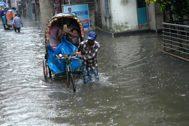 July 12, 2026, Dhaka, Dhaka, Bangladesh: A rickshaw puller pedals through a waterlogged street while carrying passengers during heavy monsoon rainfall in Dhaka, Bangladesh. Persistent downpours have inundated large parts of the capital, disrupting daily life and transportation, forcing residents to continue their routines despite widespread flooding. Dhaka Bangladesh  - ZUMAk174 20260712_zip_k174_013 Copyright: xSyedxMahabubulxKaderx