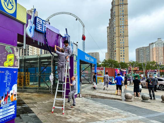 (260712) -- BEIJING, July 12, 2026 -- Staff members clear signboards destroyed by strong winds at a shopping mall in Yueqing City, east China s Zhejiang Province, July 12, 2026. Typhoon Bavi, the ninth typhoon of the year, landed on the coast of east China s Zhejiang Province at around 11:20 p.m. Saturday, according to the Zhejiang provincial meteorological observatory. The typhoon, with the maximum wind force at its center reaching 40 meters per second when landing, first churned ashore at Yuhuan City, a county-level city administered by the city of Taizhou, before making a second landfall in Yueqing City under the city of Wenzhou at around midnight. After landfall, the typhoon is expected to continue moving northwestward while weak 