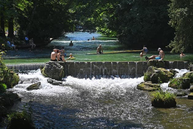 Wetterbild vom 12.07.2026 Menschen suchen Abkuehlung im Eisbach in Muenchen. Besters Sommerwetter bei Temperaturen um 30 Grad treibt die Menschen in Muenchen an die freie Luft und in den kuehlen Eisbach im Englischen Garten *** Weather photo from July 12, 2026: People seek relief from the heat in the Eisbach in Munich. Perfect summer weather, with temperatures around 30 degrees, is drawing people in Munich outdoors and into the cool Eisbach in the English Garden.