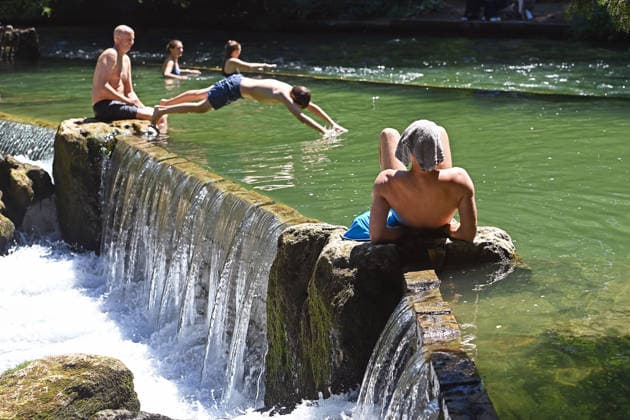 Wetterbild vom 12.07.2026 Menschen suchen Abkuehlung im Eisbach in Muenchen. Besters Sommerwetter bei Temperaturen um 30 Grad treibt die Menschen in Muenchen an die freie Luft und in den kuehlen Eisbach im Englischen Garten *** Weather photo from July 12, 2026: People seek relief from the heat in the Eisbach in Munich. Perfect summer weather, with temperatures around 30 degrees, is drawing people in Munich outdoors and into the cool Eisbach in the English Garden.