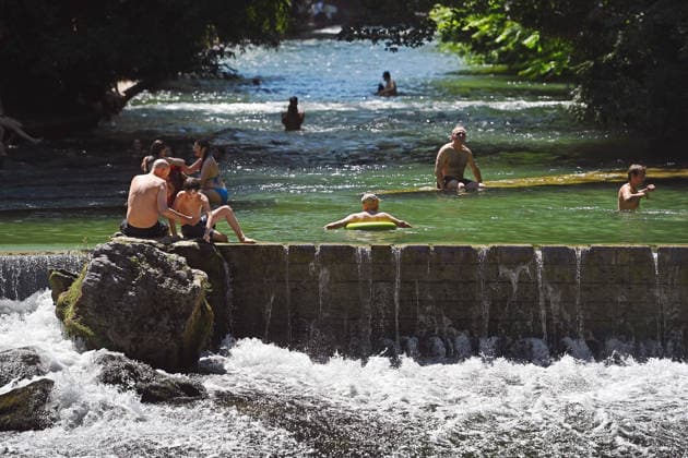 Wetterbild vom 12.07.2026 Menschen suchen Abkuehlung im Eisbach in Muenchen. Besters Sommerwetter bei Temperaturen um 30 Grad treibt die Menschen in Muenchen an die freie Luft und in den kuehlen Eisbach im Englischen Garten *** Weather photo from July 12, 2026: People seek relief from the heat in the Eisbach in Munich. Perfect summer weather, with temperatures around 30 degrees, is drawing people in Munich outdoors and into the cool Eisbach in the English Garden.