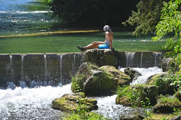 Wetterbild vom 12.07.2026 Menschen suchen Abkuehlung im Eisbach in Muenchen. Besters Sommerwetter bei Temperaturen um 30 Grad treibt die Menschen in Muenchen an die freie Luft und in den kuehlen Eisbach im Englischen Garten *** Weather photo from July 12, 2026: People seek relief from the heat in the Eisbach in Munich. Perfect summer weather, with temperatures around 30 degrees, is drawing people in Munich outdoors and into the cool Eisbach in the English Garden.