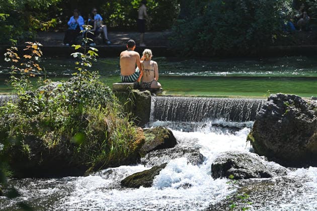 Wetterbild vom 12.07.2026 Menschen suchen Abkuehlung im Eisbach in Muenchen. Besters Sommerwetter bei Temperaturen um 30 Grad treibt die Menschen in Muenchen an die freie Luft und in den kuehlen Eisbach im Englischen Garten *** Weather photo from July 12, 2026: People seek relief from the heat in the Eisbach in Munich. Perfect summer weather, with temperatures around 30 degrees, is drawing people in Munich outdoors and into the cool Eisbach in the English Garden.