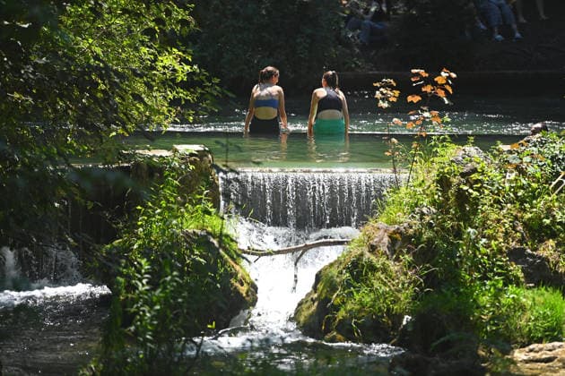 Wetterbild vom 12.07.2026 Menschen suchen Abkuehlung im Eisbach in Muenchen. Besters Sommerwetter bei Temperaturen um 30 Grad treibt die Menschen in Muenchen an die freie Luft und in den kuehlen Eisbach im Englischen Garten *** Weather photo from July 12, 2026: People seek relief from the heat in the Eisbach in Munich. Perfect summer weather, with temperatures around 30 degrees, is drawing people in Munich outdoors and into the cool Eisbach in the English Garden.