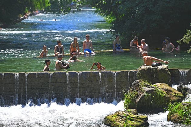 Wetterbild vom 12.07.2026 Menschen suchen Abkuehlung im Eisbach in Muenchen. Besters Sommerwetter bei Temperaturen um 30 Grad treibt die Menschen in Muenchen an die freie Luft und in den kuehlen Eisbach im Englischen Garten *** Weather photo from July 12, 2026: People seek relief from the heat in the Eisbach in Munich. Perfect summer weather, with temperatures around 30 degrees, is drawing people in Munich outdoors and into the cool Eisbach in the English Garden.