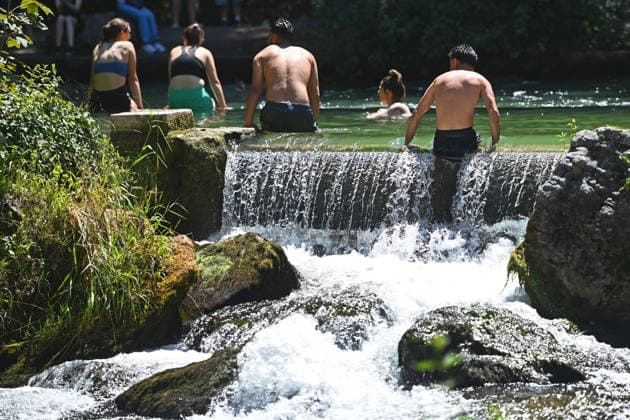 Wetterbild vom 12.07.2026 Menschen suchen Abkuehlung im Eisbach in Muenchen. Besters Sommerwetter bei Temperaturen um 30 Grad treibt die Menschen in Muenchen an die freie Luft und in den kuehlen Eisbach im Englischen Garten *** Weather photo from July 12, 2026: People seek relief from the heat in the Eisbach in Munich. Perfect summer weather, with temperatures around 30 degrees, is drawing people in Munich outdoors and into the cool Eisbach in the English Garden.