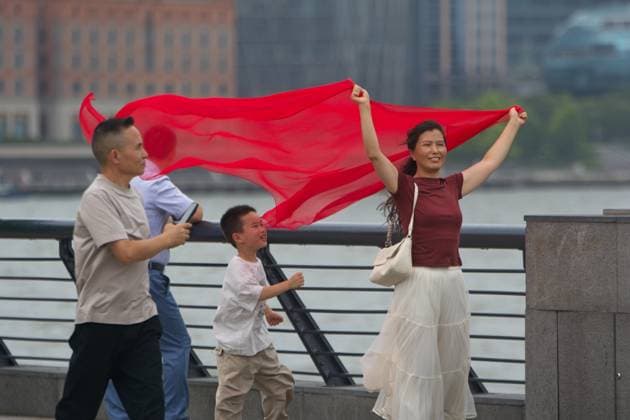 Aftermath Of Super Typhoon Bavi In Shanghai A woman takes pictures with her scarf blowing in the wind at the Bund in Shanghai, China, on July 12, 2026, as Super Typhoon Bavi makes landfall in Zhejiang province, China. shanghai China  Copyright: xYingxTangx originalFilename: tang-shanghai260712_npJNA.jpg