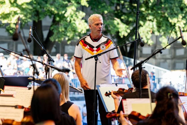 Klassik!Picknick mit dem Beethoven Orchester auf dem Kunst!Rasen Bonn Generalmusikdirektor Dirk KAFTAN im Deutschland Trikot - Das Beethoven Orchester Bonn unter der Leitung von Generalmusikdirektor Dirk KAFTAN beim Open-Air-Konzert KLASSIK!PICKNICK auf dem Kunst!Rasen Bonn-Gronau. Das Sommerprogramm steht unter dem Motto Fußball - passend zur WM 2026. Die Konzertreihe findet am Rande der Rheinaue am Bonner Rheinufer statt. Bonn Gronau Nordrhein-Westfalen Deutschland *** Classical Picnic with the Beethoven Orchestra on the Kunst Rasen in Bonn; General Music Director Dirk KAFTAN in the Germany jersey. The Beethoven Orchestra Bonn, conducted by General Music Director Dirk KAFTAN, at the open-air concert Classical Picnic on the Kunst Rasen Copyright: xMarcxJohnx