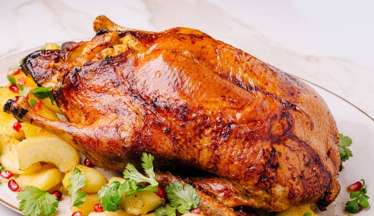 Gebratene Ente mit Kartoffeln und Granatapfel zum Festtagsessen Whole roasted duck serving with roasted potatoes, fresh pomegranate seeds, and herbs (License=RF) Copyright: xZoonar.com AntonxDobreax 25286716