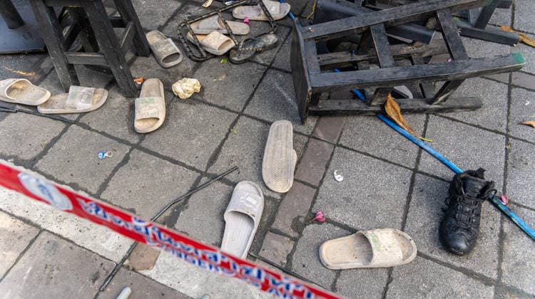 Deadly Fire at Rong Beer Na Lat Phrao Pub in Bangkok - 13 Jul 2026 A close-up view of shoes left on the sidewalk outside the Rong Beer Na Lat Phrao pub after the fire, surrounded by debris, damaged furniture, and red warning tape marking the dangerous area on Lat Phrao Road in Bangkok. The aftermath of a deadly fire at the Rong Beer Na Lat Phrao pub in Bangkok on 13 July 2026. The blaze killed at least 27 people and injured dozens. Authorities are investigating the cause of the fire. Bangkok Thailand Copyright: xNathaliexJamoisx xSOPAxImagesx NathalieJamois_FirePub_13-07-26-12