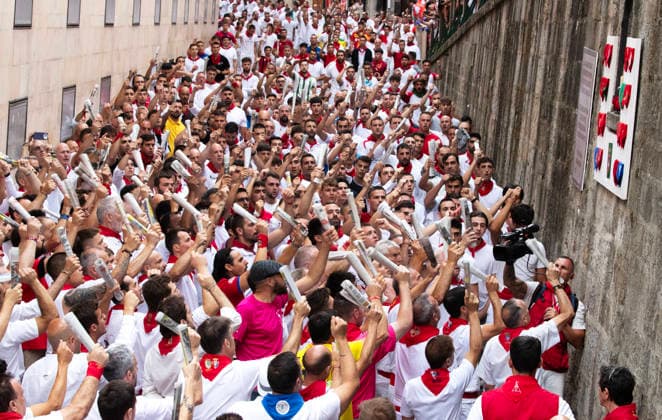 Bull runners lift their rolled up newspapers as they sing a song to San Fermin, asking him for this protection, before the start of the seventh running-of-the-bulls, or encierro, during the First de San Fermin in Pamplon, northern Spain, during the Fiesta de San Fermin on Monday, July 13, 2026.  PAM2026071300 JimxHollander