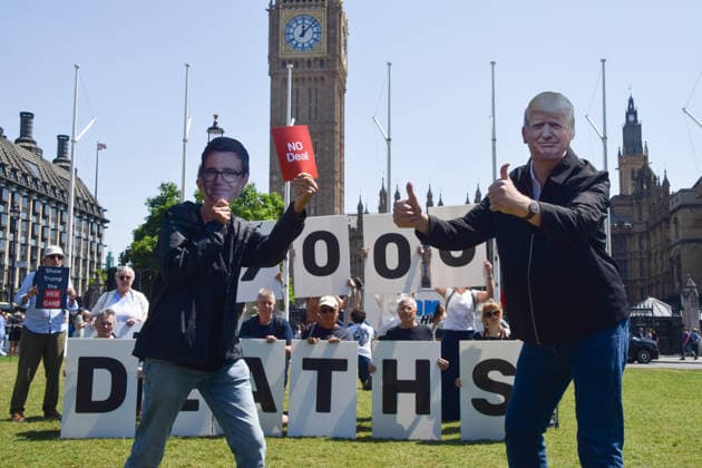 July 13, 2026, London, England, United Kingdom: An activist wearing an Andy Burnham mask shows a no deal red card to an activist wearing a Donald Trump mask during a protest in Parliament Square against the US-UK drug deal. An analysis has suggested that the trade deal could lead to 229,000 excess deaths in England as a result of diverting billions of pounds from essential NHS services to pay for new medicines. London United Kingdom - ZUMAv130 20260713_zip_v130_004 Copyright: xVukxValcicx