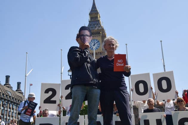 July 13, 2026, London, England, United Kingdom: Baroness JENNY JONES holds a no deal red card next to an activist wearing an Andy Burnham mask during a protest in Parliament Square against the US-UK drug deal. An analysis has suggested that the trade deal could lead to 229,000 excess deaths in England as a result of diverting billions of pounds from essential NHS services to pay for new medicines. London United Kingdom - ZUMAv130 20260713_zip_v130_006 Copyright: xVukxValcicx