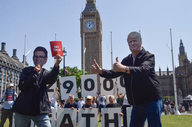 July 13, 2026, London, England, United Kingdom: An activist wearing an Andy Burnham mask shows a no deal red card to an activist wearing a Donald Trump mask during a protest in Parliament Square against the US-UK drug deal. An analysis has suggested that the trade deal could lead to 229,000 excess deaths in England as a result of diverting billions of pounds from essential NHS services to pay for new medicines. London United Kingdom  - ZUMAv130 20260713_zip_v130_005 Copyright: xVukxValcicx
