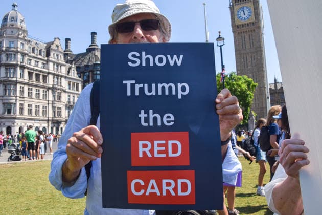 July 13, 2026, London, England, United Kingdom: An activist holds a Show Trump the red card placard during a protest in Parliament Square against the US-UK drug deal. An analysis has suggested that the trade deal could lead to 229,000 excess deaths in England as a result of diverting billions of pounds from essential NHS services to pay for new medicines. London United Kingdom  - ZUMAv130 20260713_zip_v130_009 Copyright: xVukxValcicx