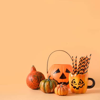 Lustige Halloween-Partydekoration, Kürbisse, Becher mit Trinkhalm. Halloween festive party decorations, candy bowl, pumpkins, funny mug with drinking straw on orange background. Square composition with copy space. (License=RF) Copyright: xZoonar.com SvetlanaxLazhkox 25303778