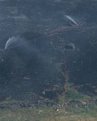 News Bilder des Tages Firemen sit by water hose attempting to put out smouldering moorland close to Dove Stone Reservoir in Greater Manchester on 13 July 2026. Greater Manchester Police have arrested a woman in connection with a large moorland fire at Dove Stone Reservoir in Greenfield. The blaze, burning since Saturday, is under active investigation, with officers following leads regarding reports of fireworks nearby. The 20-year-old suspect remains in custody as the cause of the fire is yet to be officially determined. Oldham Greater Manchester England Dovestone Reservoir  Copyright: xMattxWilkinsonx